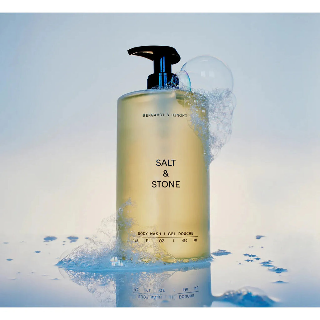 A bottle of salt & stone body wash with a soap bubble on top against a neutral background.