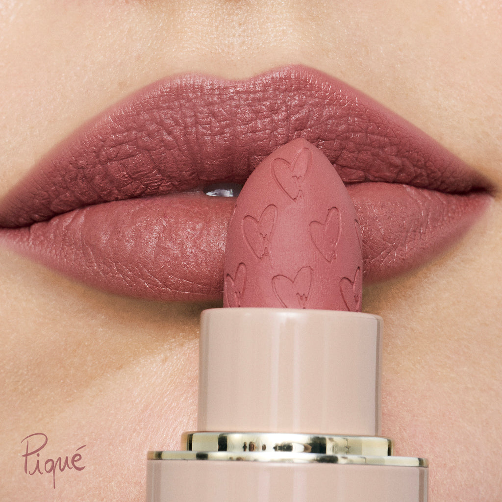Close-up of lips with matte lipstick and a matching lipstick bullet decorated with hearts.