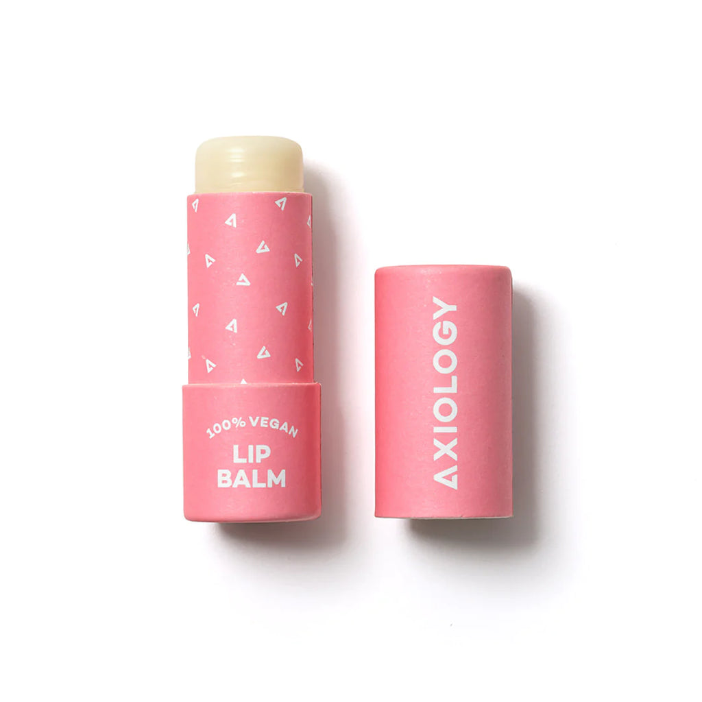 A pink Axiology vegan lip balm with its cap placed to the side, isolated on a white background.