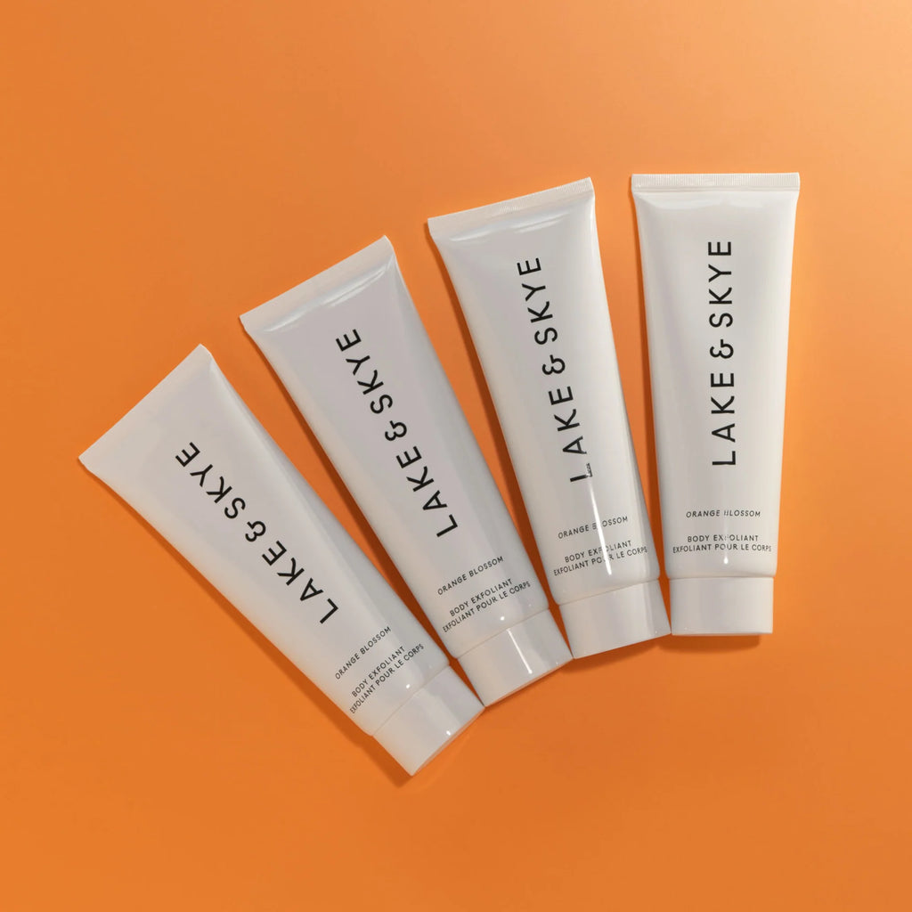 Four tubes of lake & skye beauty products arranged in an orderly fashion on an orange background.