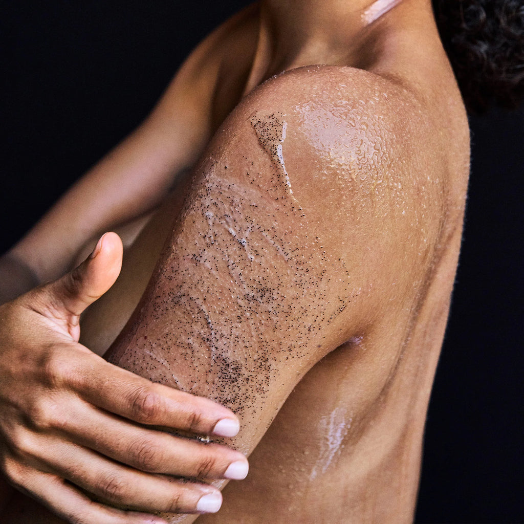 A close-up of a person exfoliating their skin with a scrub.