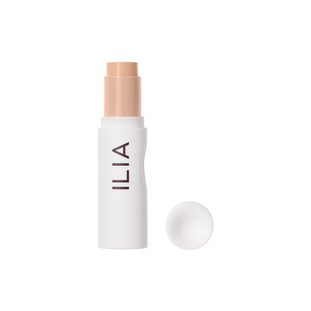 Ilia branded foundation stick with cap removed, isolated on a white background.