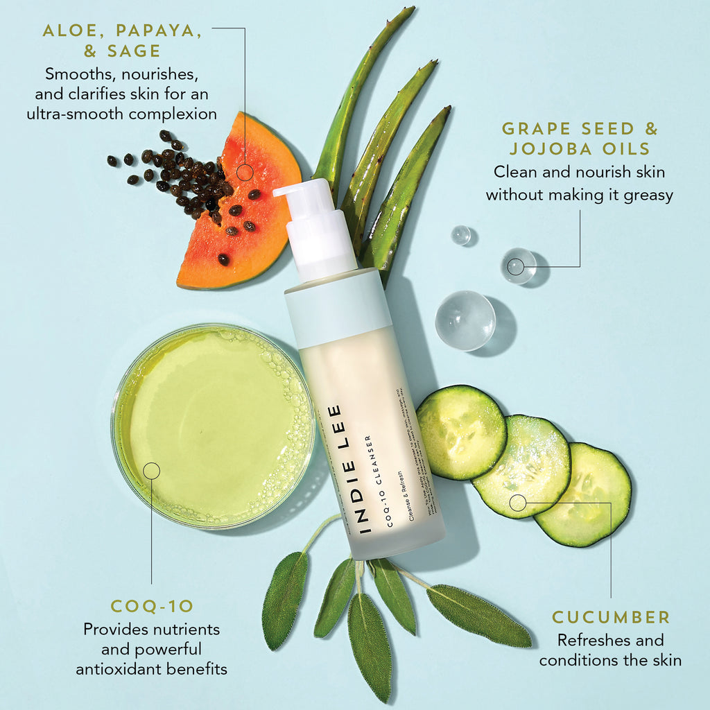 Product advertisement featuring a bottle of Indie Lee COQ-10 Cleanser surrounded by slices of papaya and aloe, with text highlighting benefits of Jojoba Seed Oil, Grape Seed Oil, and ingredients.