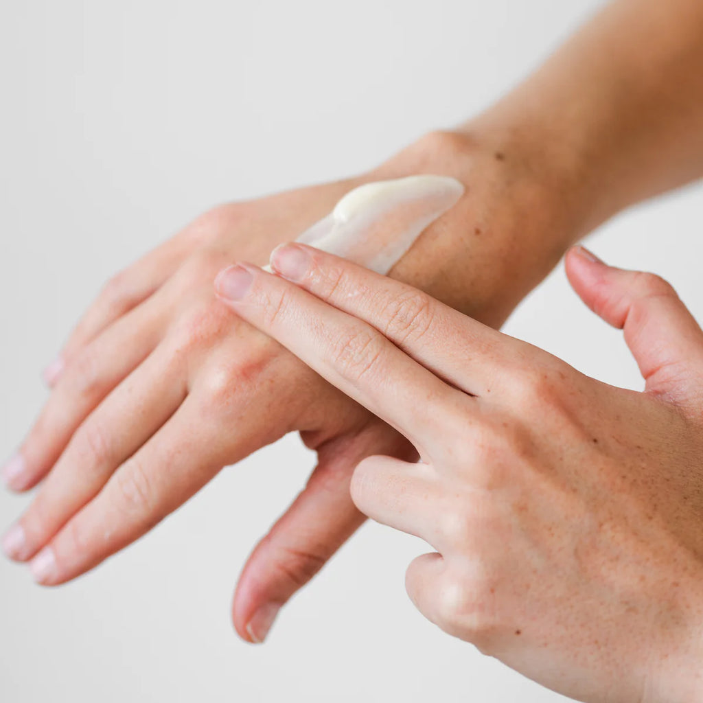 Applying moisturizer to hands against a white background.