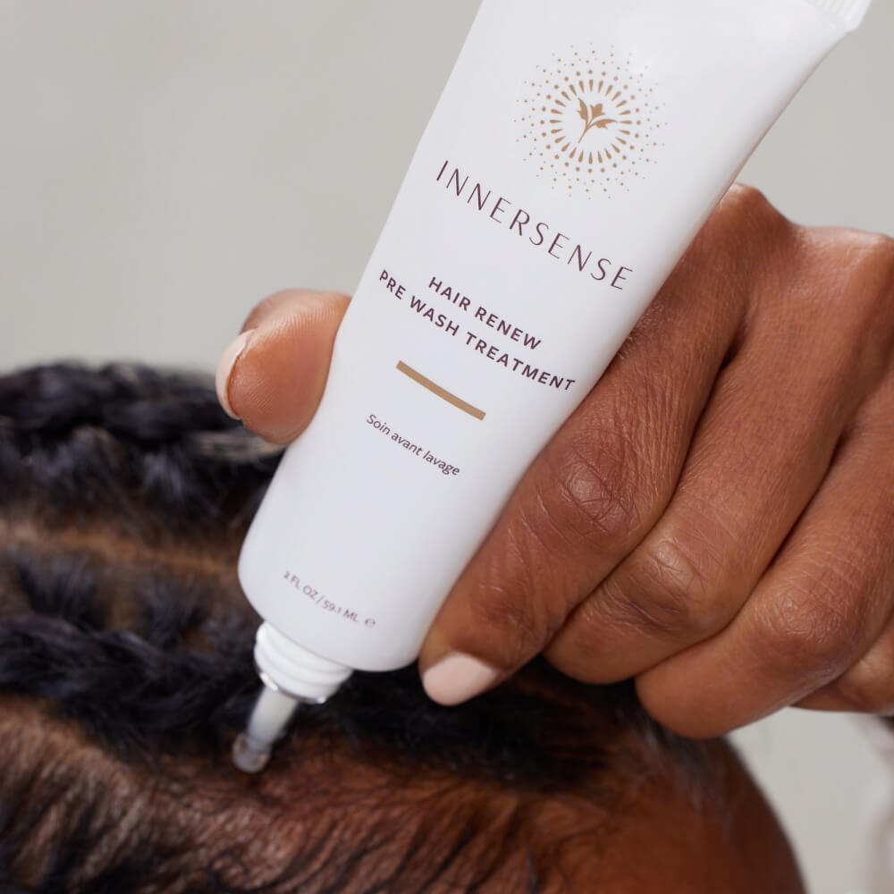 Applying scalp treatment from a tube to hair roots.