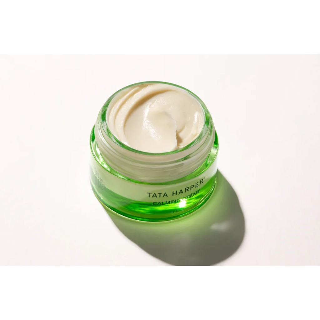 Open jar of Tata Harper Superkind Calming Cream on a light background, showcasing its creamy texture inside a green glass container designed for stressed skin.