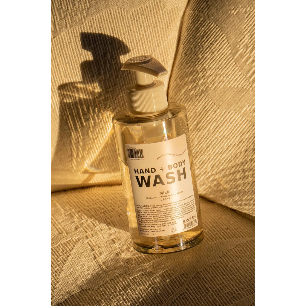 A bottle of hand and body wash placed on a textured surface in sunlight creating a shadow.