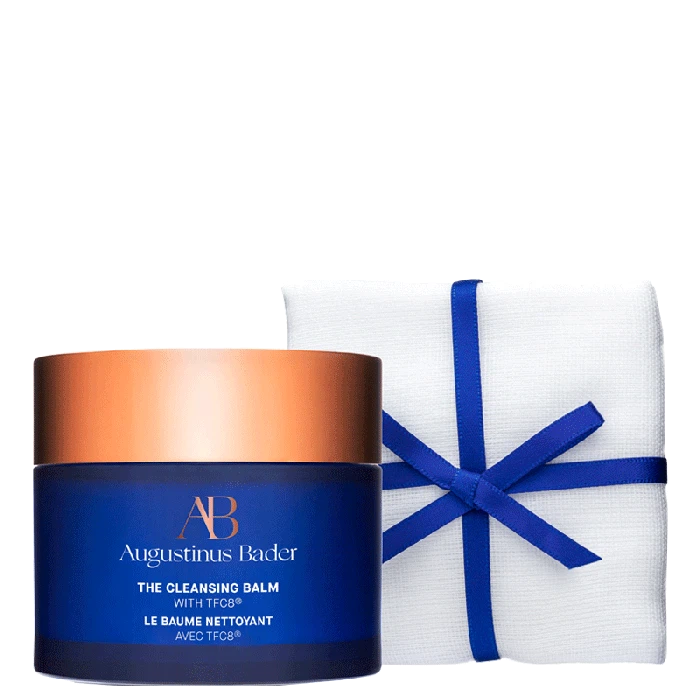 A jar of augustinus bader skincare product with a white cloth tied with a blue ribbon beside it.