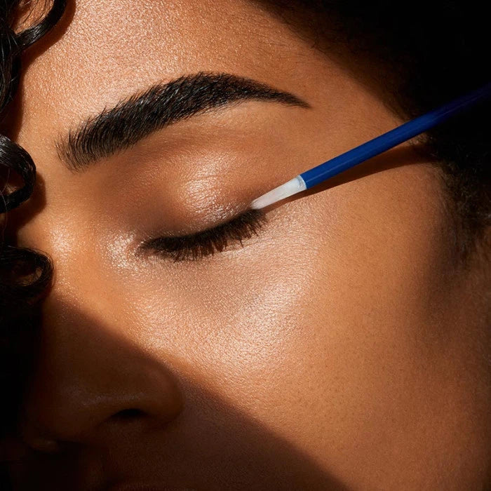 Applying eyeliner with precision using a fine brush.