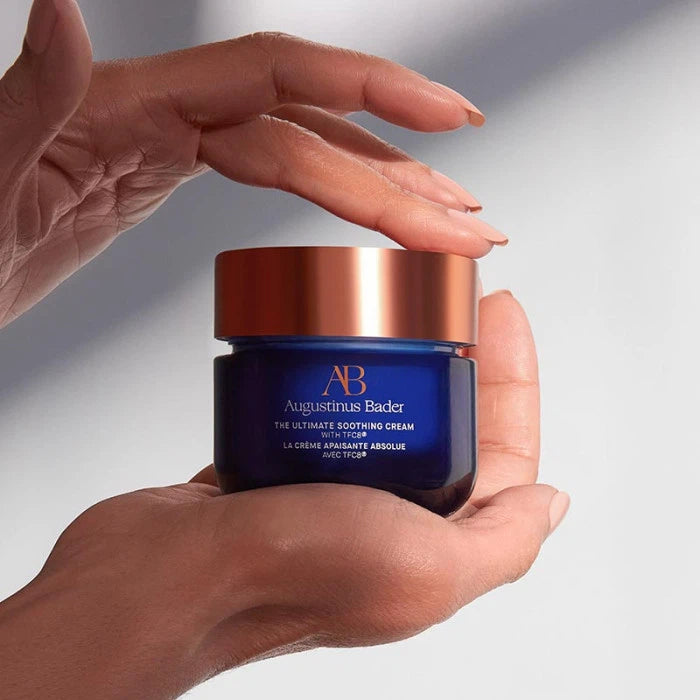 Person holding a jar of augustinus bader skincare cream.