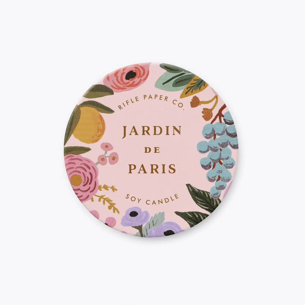 A round label for a "jardin de paris" soy candle by rifle paper co. with a floral design on a pink background.