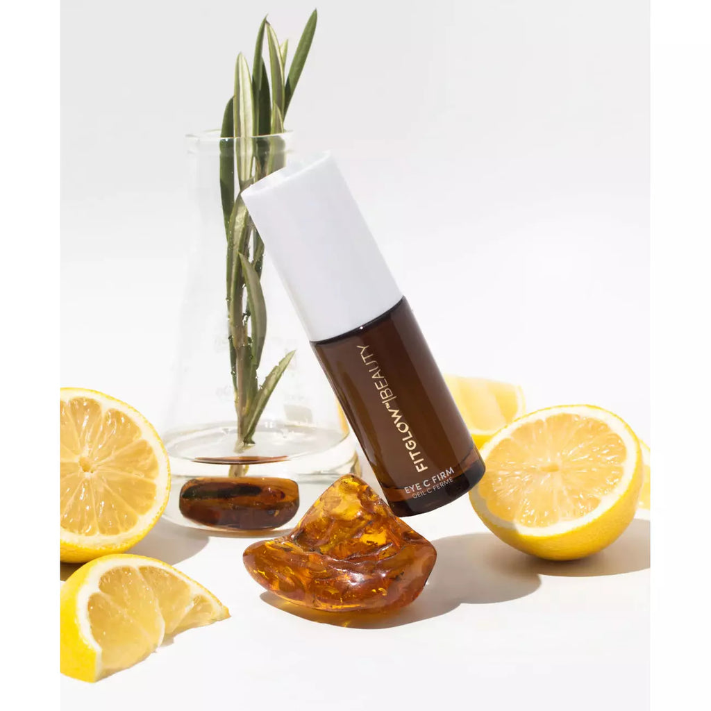 A bottle of face cream with lemons and amber resin on a white background.