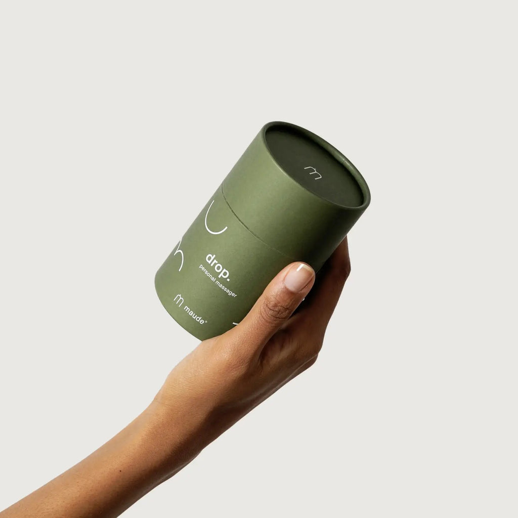 Hand holding a green cylindrical container against a neutral background.