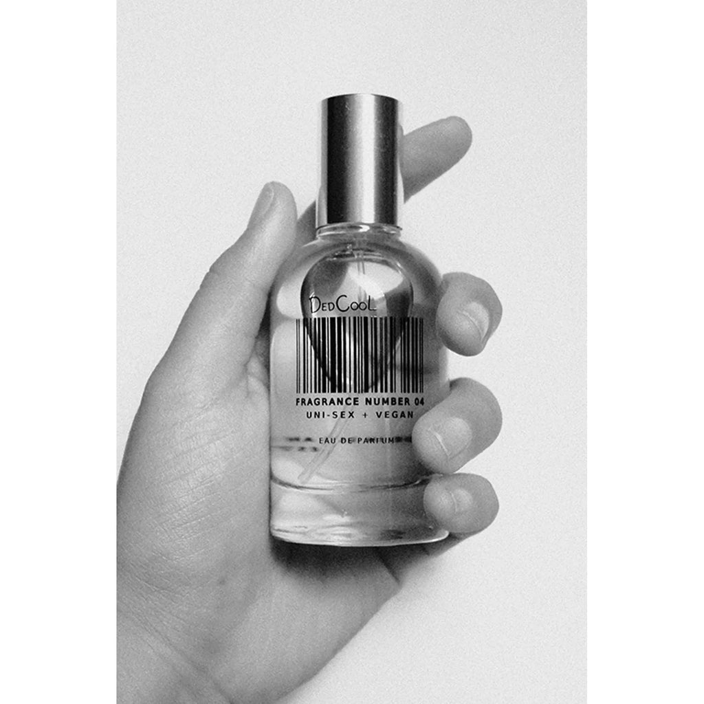 A hand holding a bottle of "decool fragrance number 04" vegan perfume.