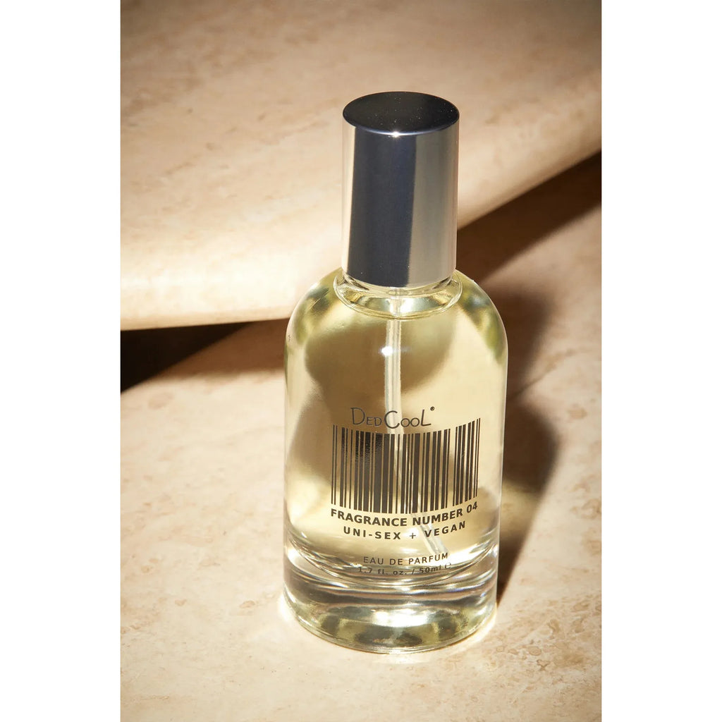 A bottle of dedcool unisex vegan perfume resting on a beige surface.