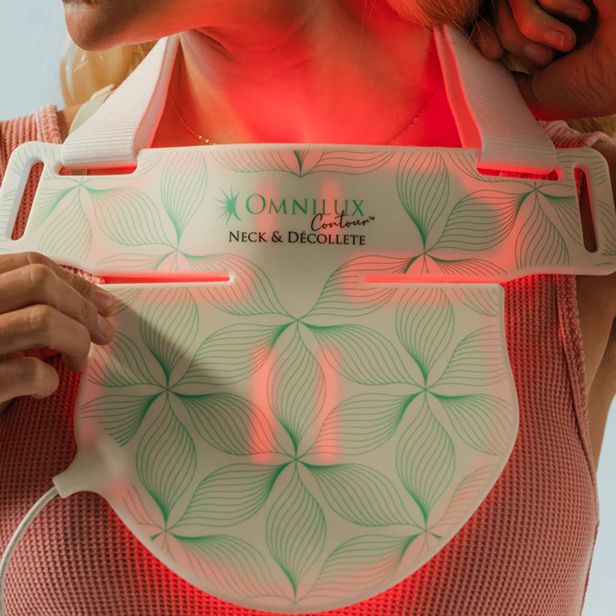 A person using an omnillux contour led light therapy device for neck and decollete treatment.