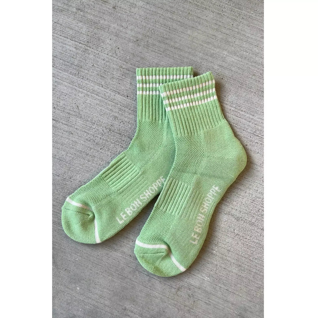 A pair of green socks with white stripes on a grey background.