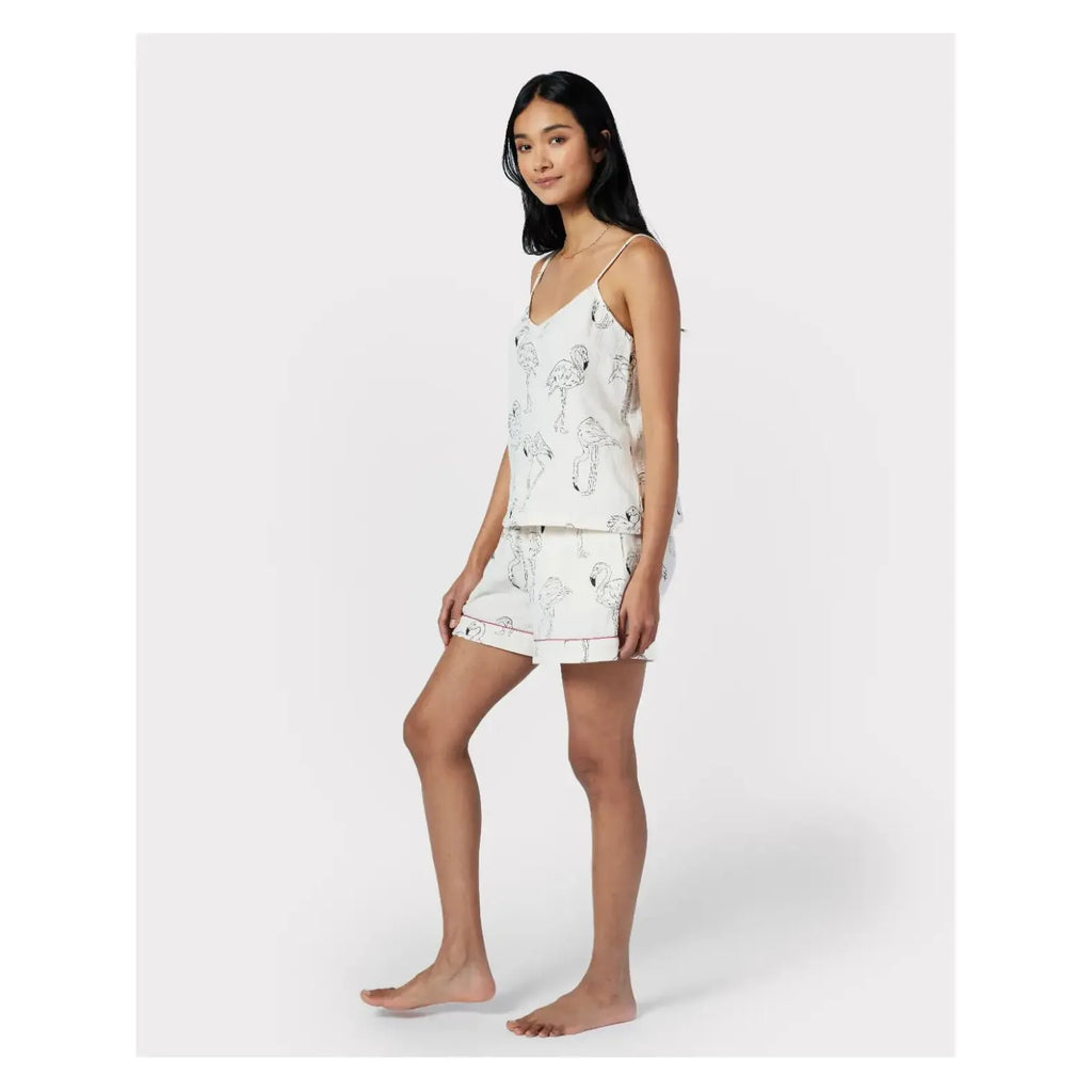 A person stands wearing a Chelsea Peers Cotton Cheesecloth Flamingo Sketch Print Cami Short Pajama Set. The lightweight cotton cheesecloth fabric ensures comfort. The background is plain white.