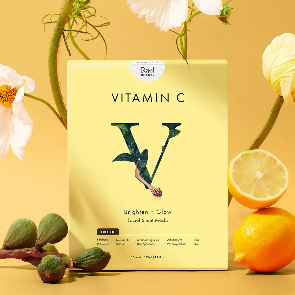 A pack of rael beauty vitamin c facial sheet masks presented with fresh flowers and citrus fruits against a warm yellow background.