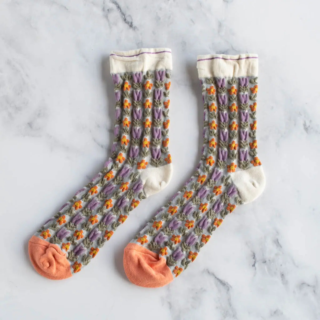 A pair of patterned socks with purple and orange details displayed on a marble surface.