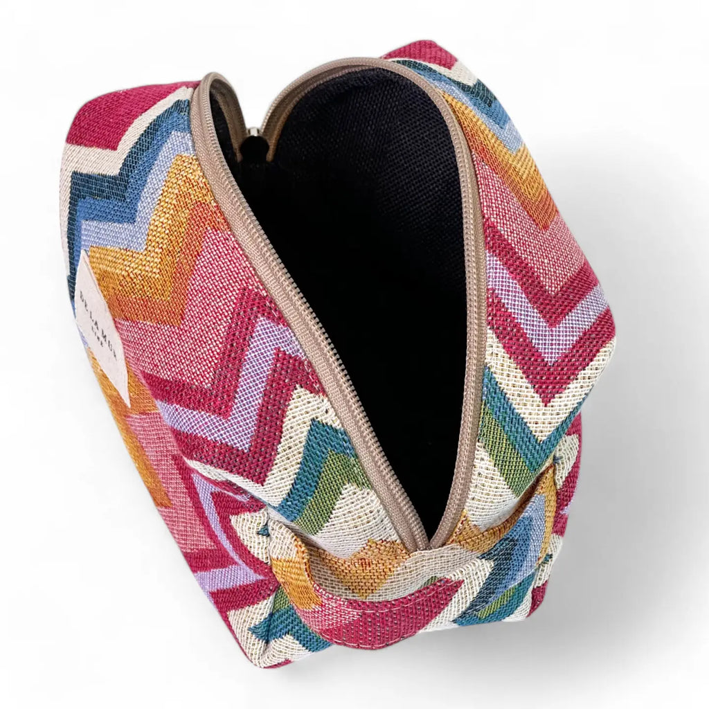 Medium toiletry bag with a zipper at the top and a side handle. Made with thick jacquard fabric with a zigzag pattern in pink and blue tones. Ideal for storing makeup, facial creams, and small bottles.
