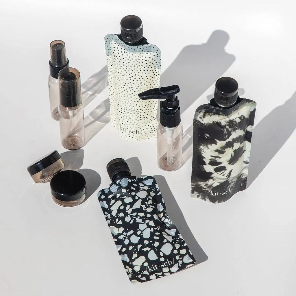 Assorted reusable travel-size toiletry bottles on a bright background.