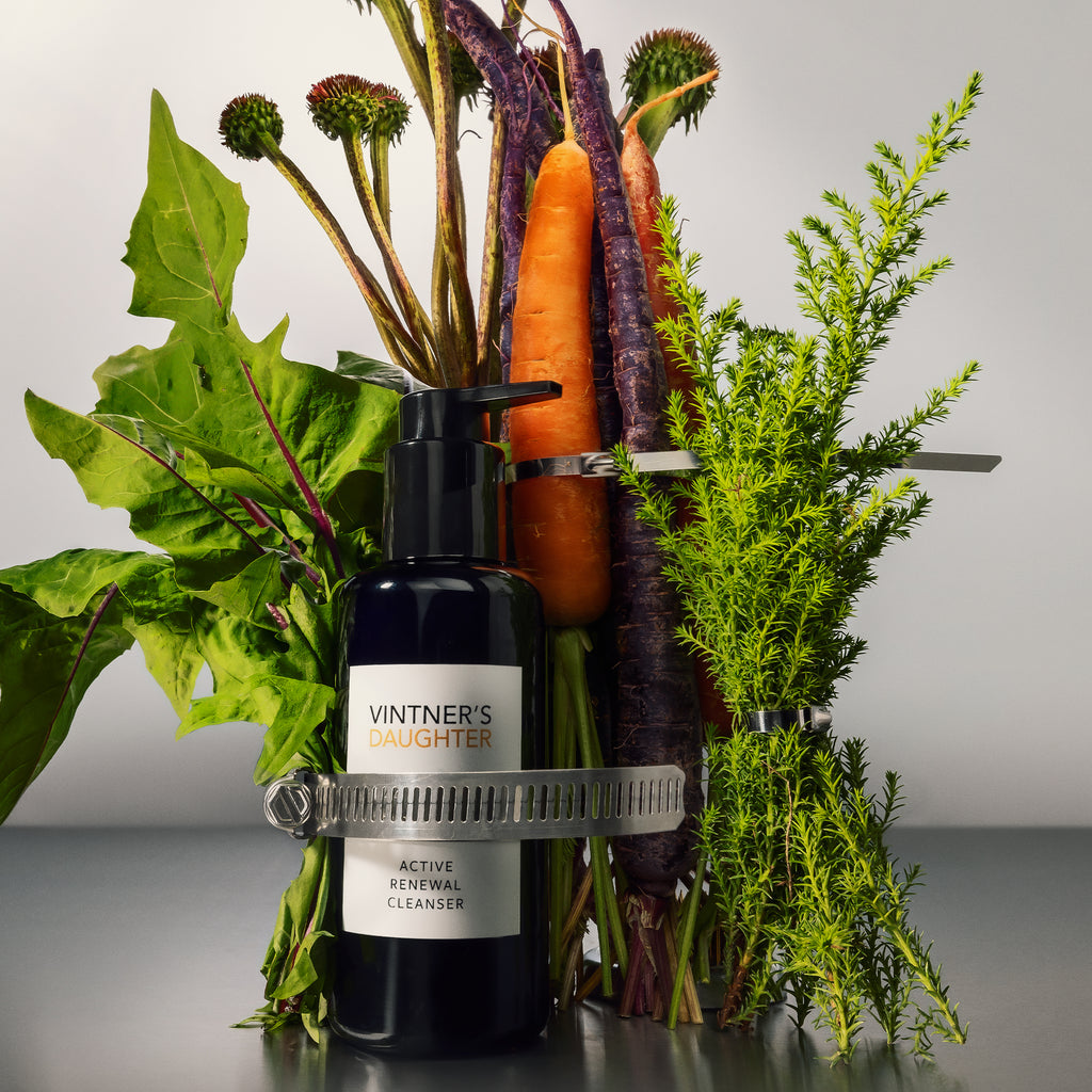 A bottle of vintner's daughter active treatment essence beside fresh vegetables.