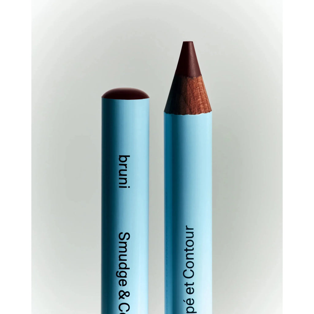 Two cosmetic pencils standing side by side against a white background.