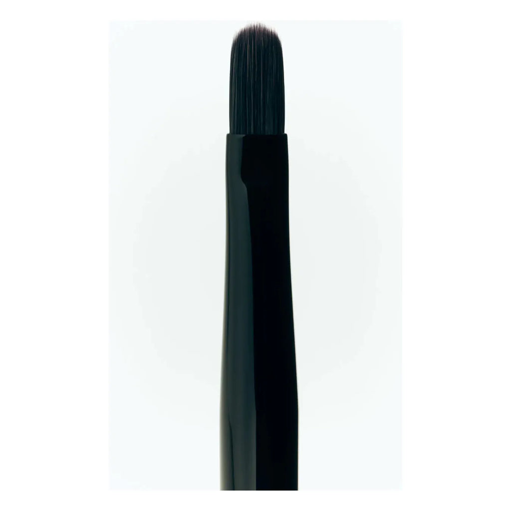 A close-up of a single black makeup brush against a white background.
