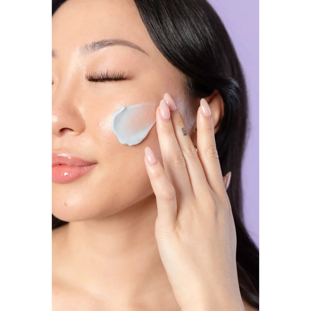 Woman applying facial cream to her cheek.