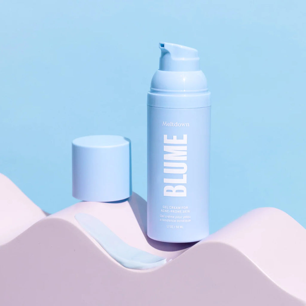 A bottle of blume meltdown acne treatment oil against a pastel blue background.
