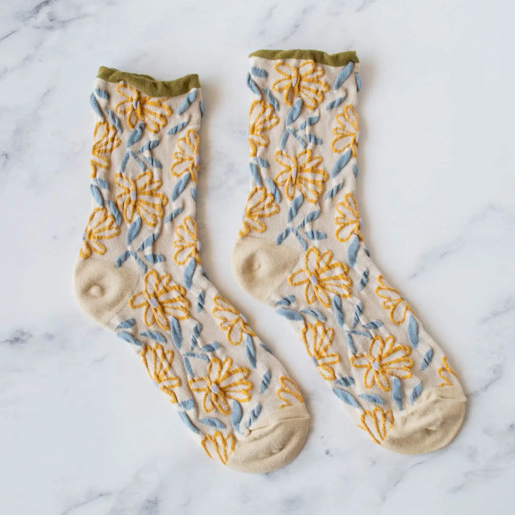 A pair of floral patterned socks on a marble surface.