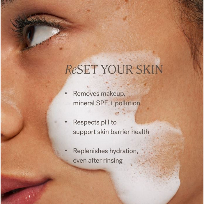 Close-up of a woman's face partially covered with a foamy cleanser, alongside text promoting the benefits of a skin care product.