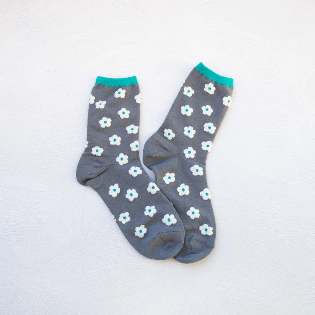 A pair of gray socks with blue and white floral patterns on a white background.