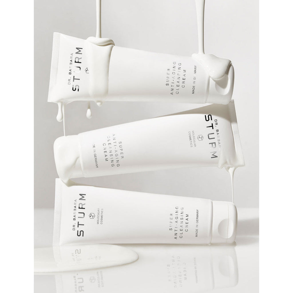 Four tubes of dr. barbara sturm skincare cream with product oozing out against a reflective surface.