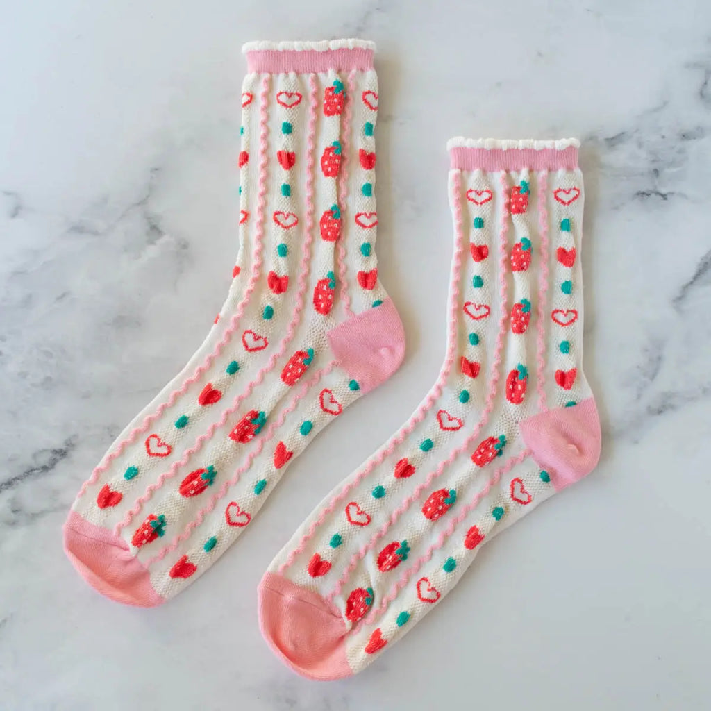 A pair of white crew socks with pink heels, toes, and cuffs, adorned with red hearts and green cacti designs.