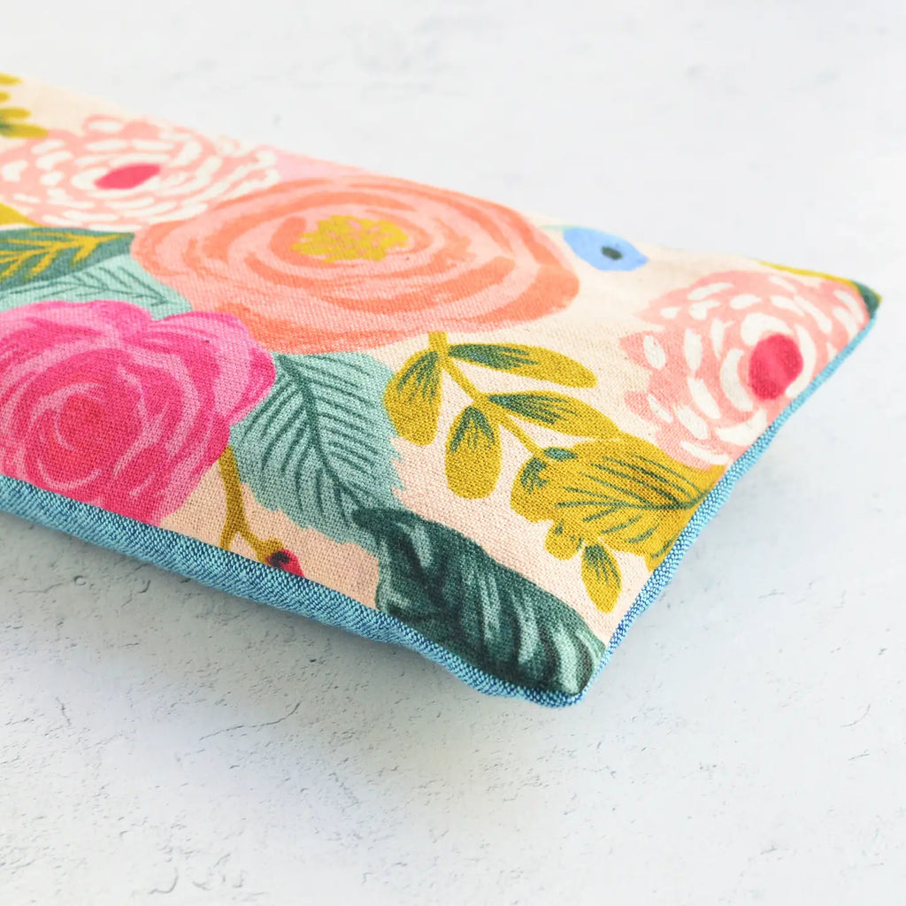 A colorful floral-patterned fabric pouch on a textured surface.