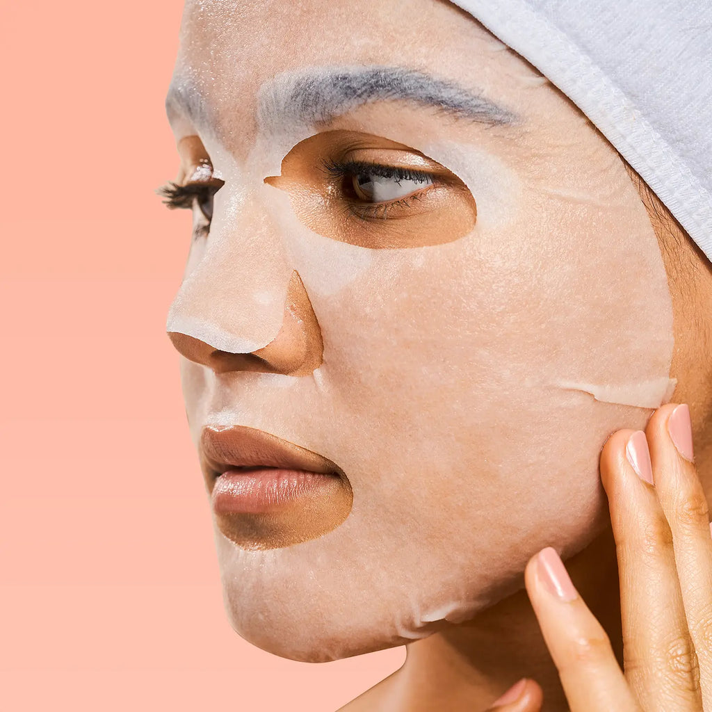 A person using a facial sheet mask for skin care.