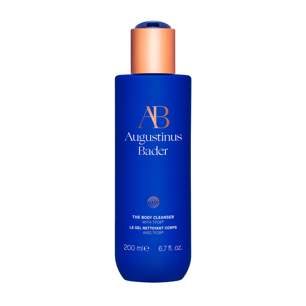 A bottle of augustinus bader body lotion with a blue label and copper-colored cap.