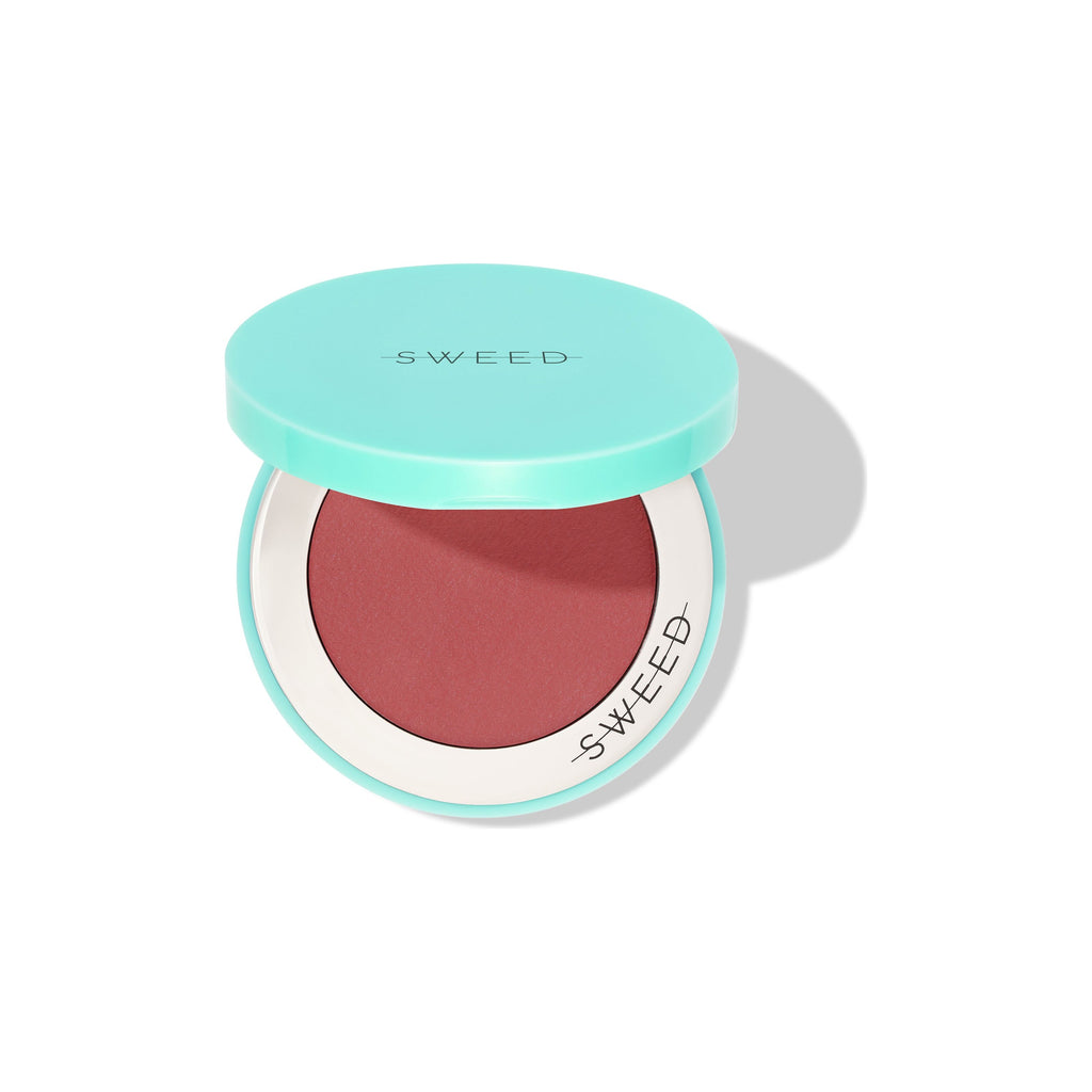A compact blush with a turquoise lid and a terracotta hue.