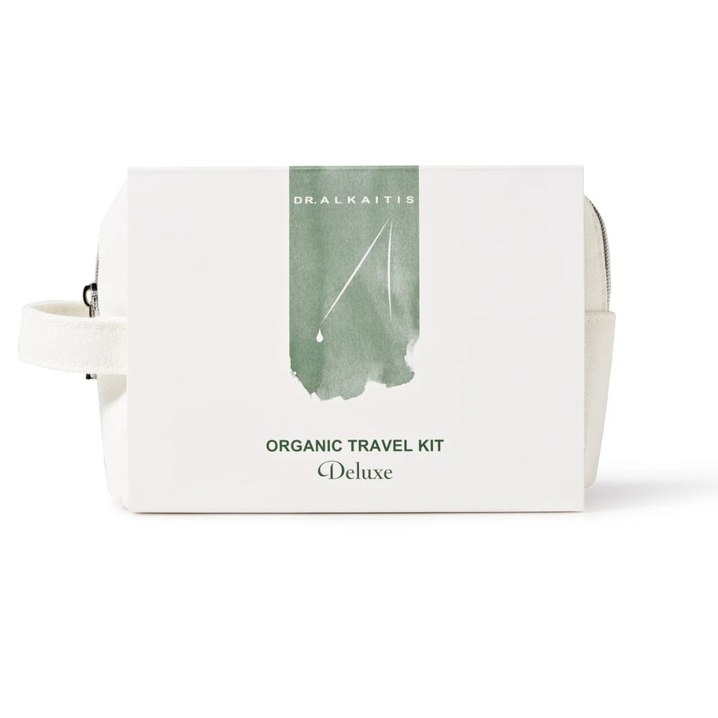 White boxed set labeled "Dr. Alkaitis Organic Travel Kit Deluxe" placed on a white background, perfect for eco-conscious travelers seeking TSA-approved convenience.