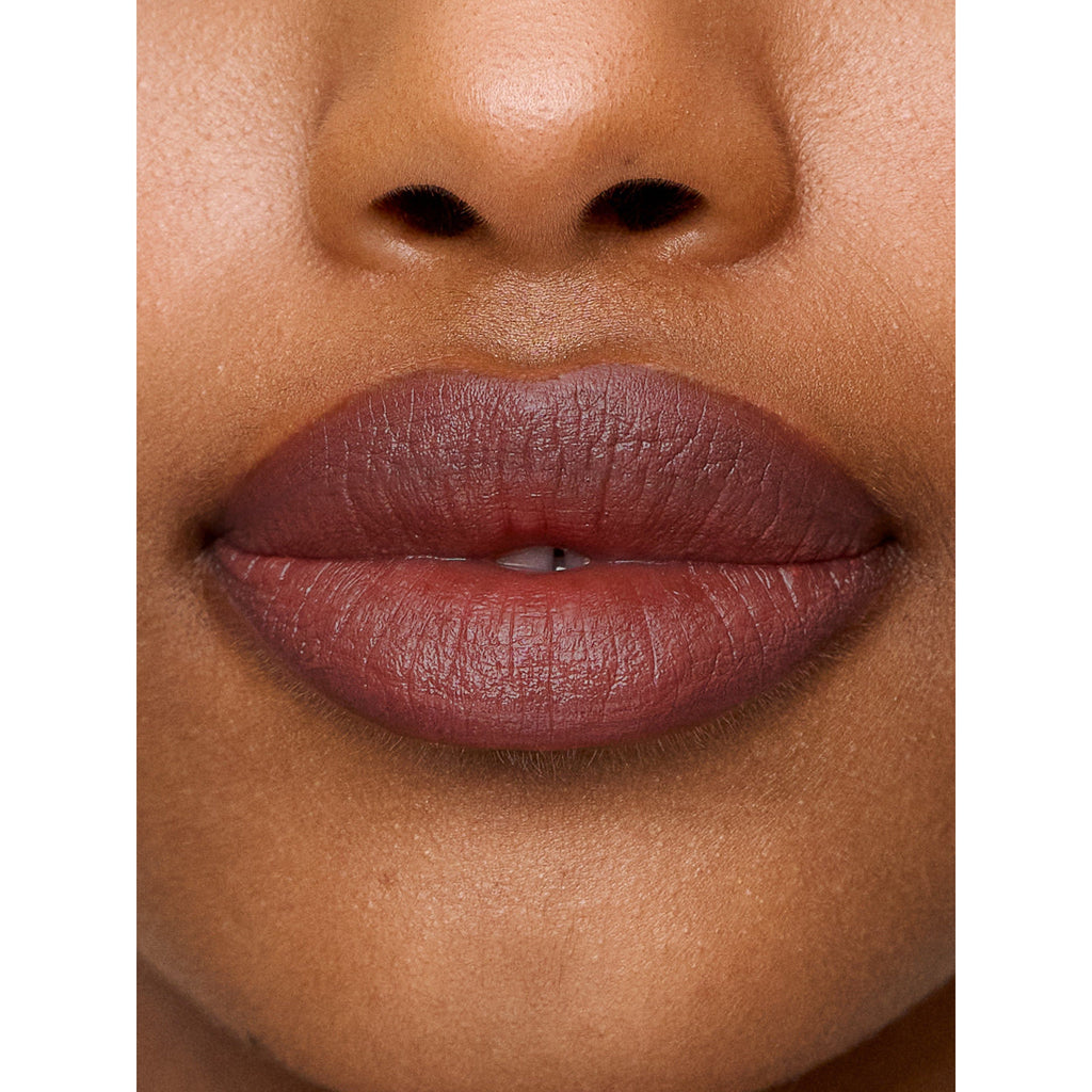 Close-up of a person's lips with matte lipstick, slightly parted, and the nose visible above.