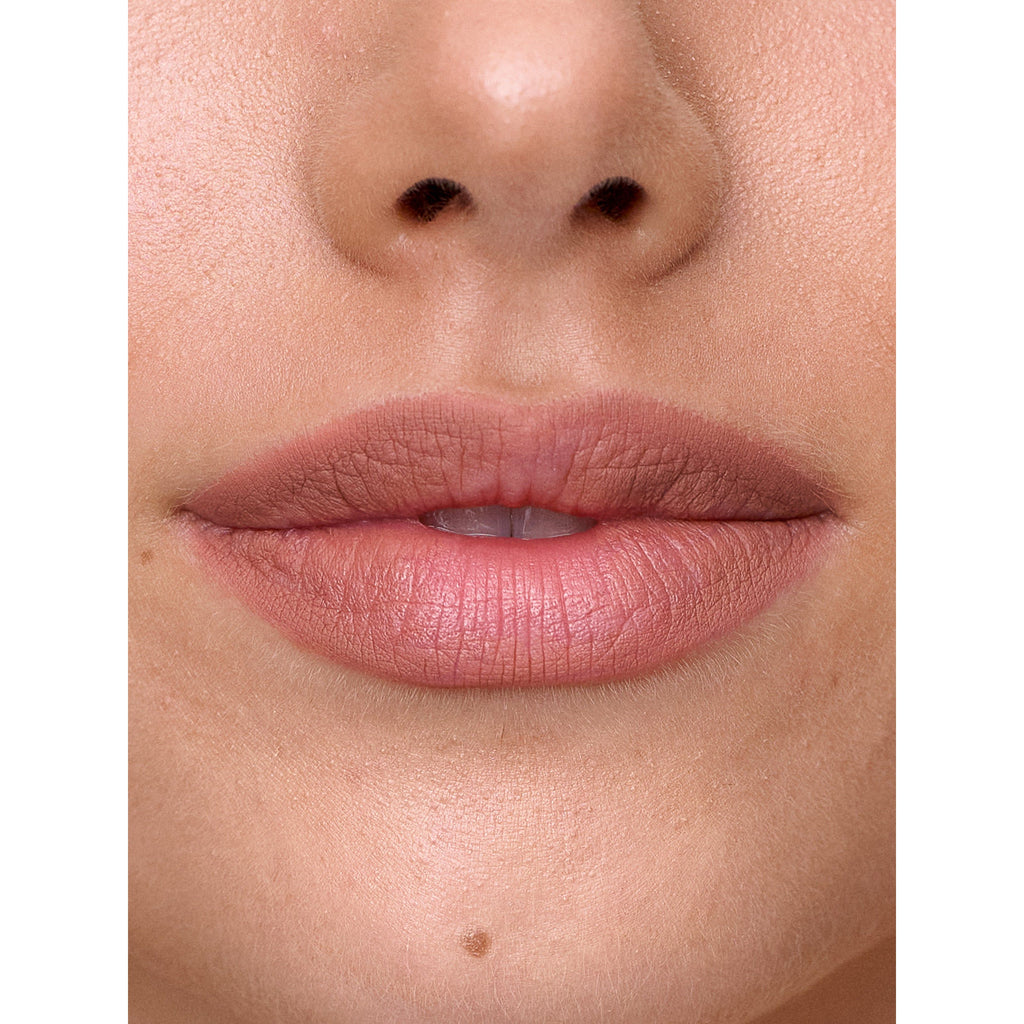 Close-up of a person's lips with natural-colored lipstick, nose, and chin visible.