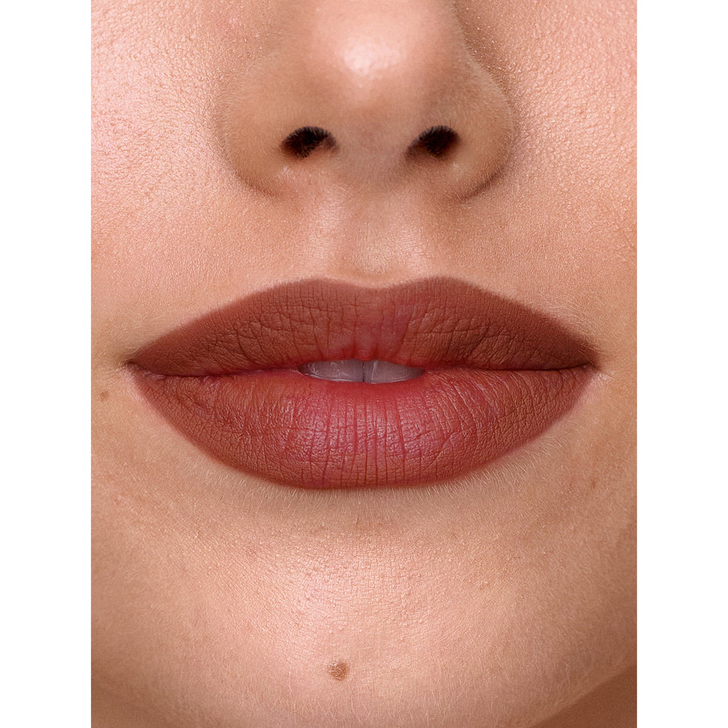 Close-up of a person's lips with matte lipstick, and the bottom of their nose visible.