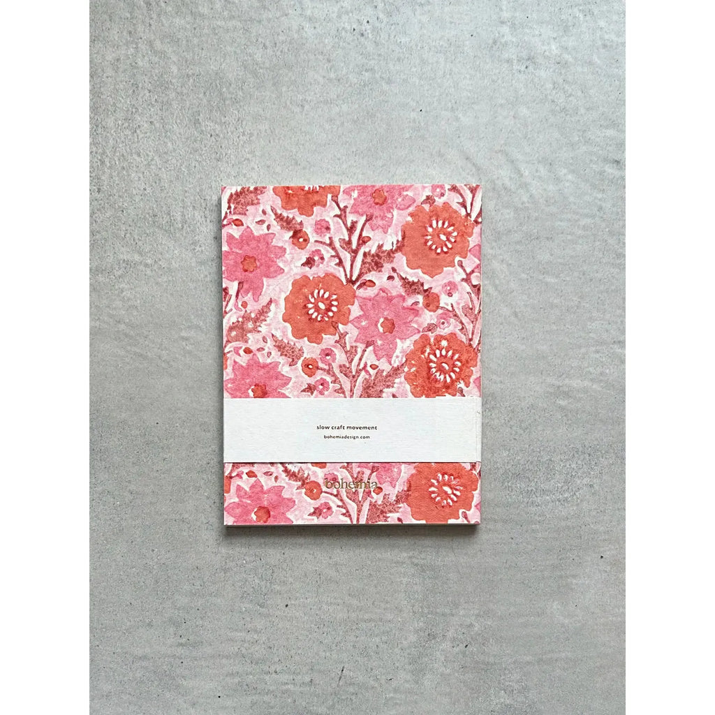 A floral-patterned journal with a white label lies on a gray background.