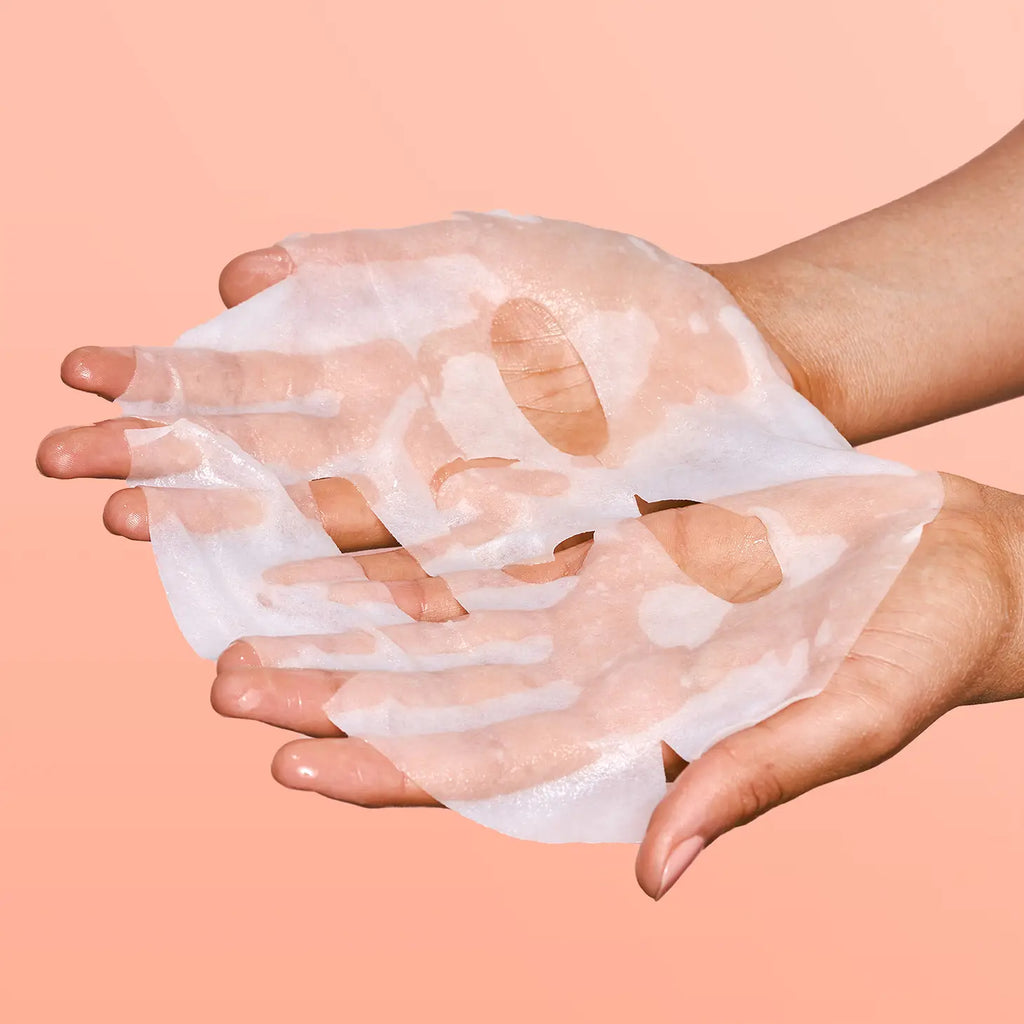 Two hands holding a transparent, peeling face mask against a solid backdrop.
