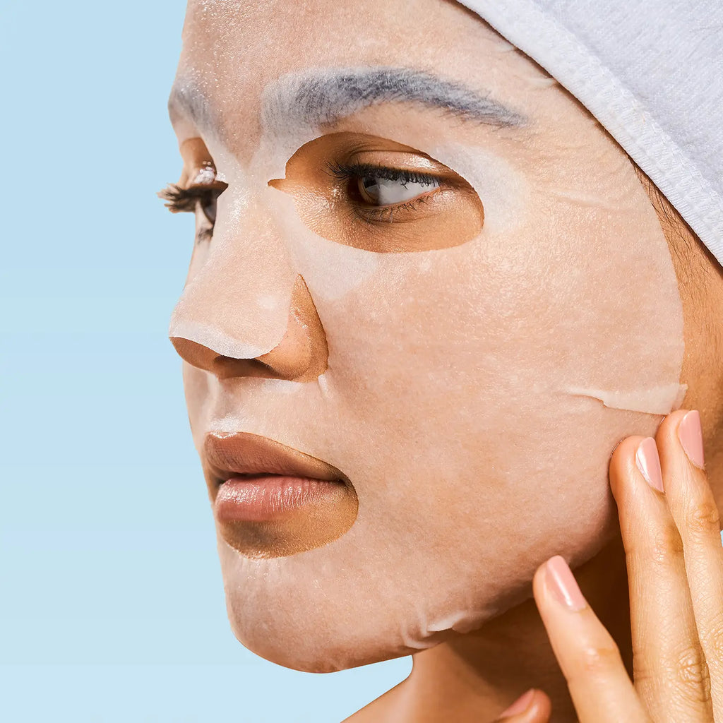 Woman with a facial sheet mask against a blue background.