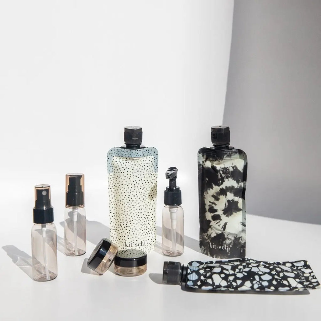 Assorted patterned cosmetic bottles and containers on a light background.