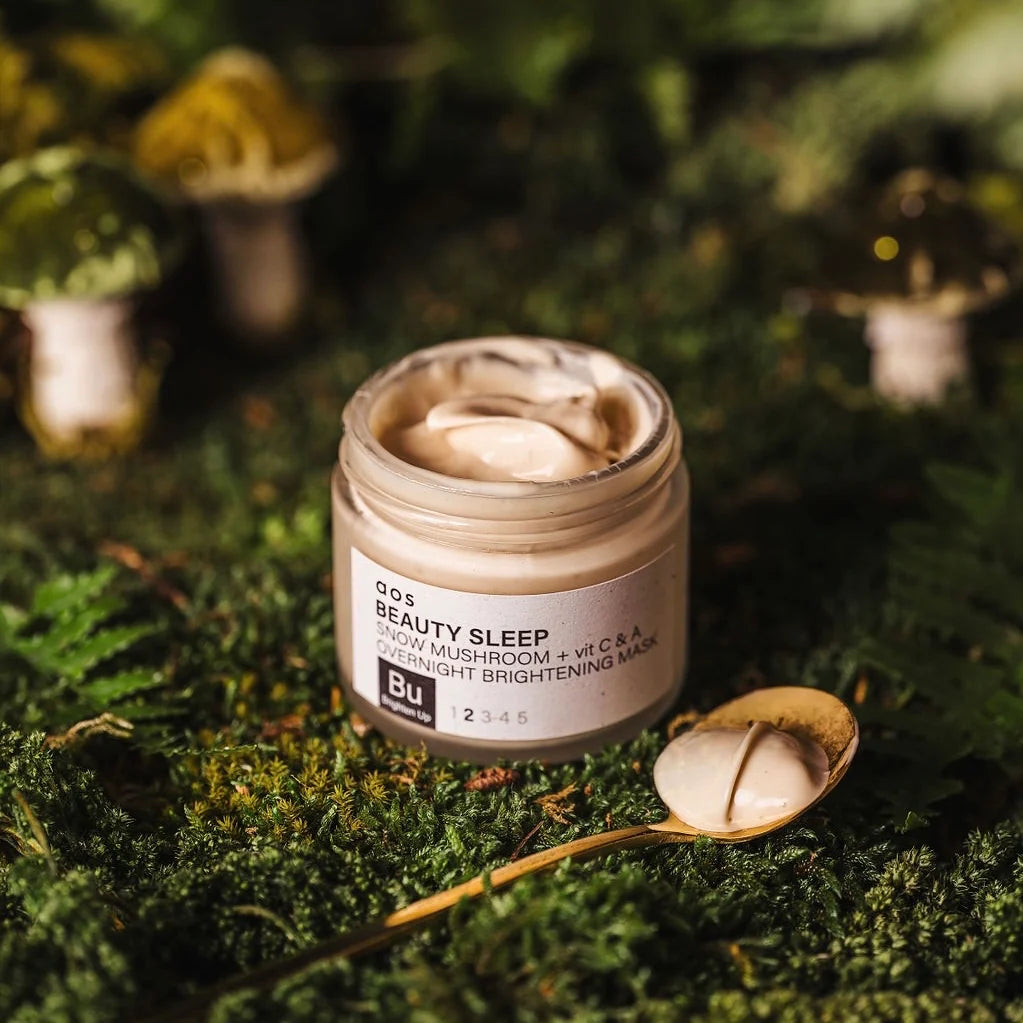 Jar of overnight beauty sleep cream with mushroom and vitamin c on a bed of moss with a small, open cap next to it.