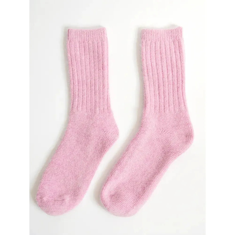 A pair of pink knitted socks laid flat on a white background.